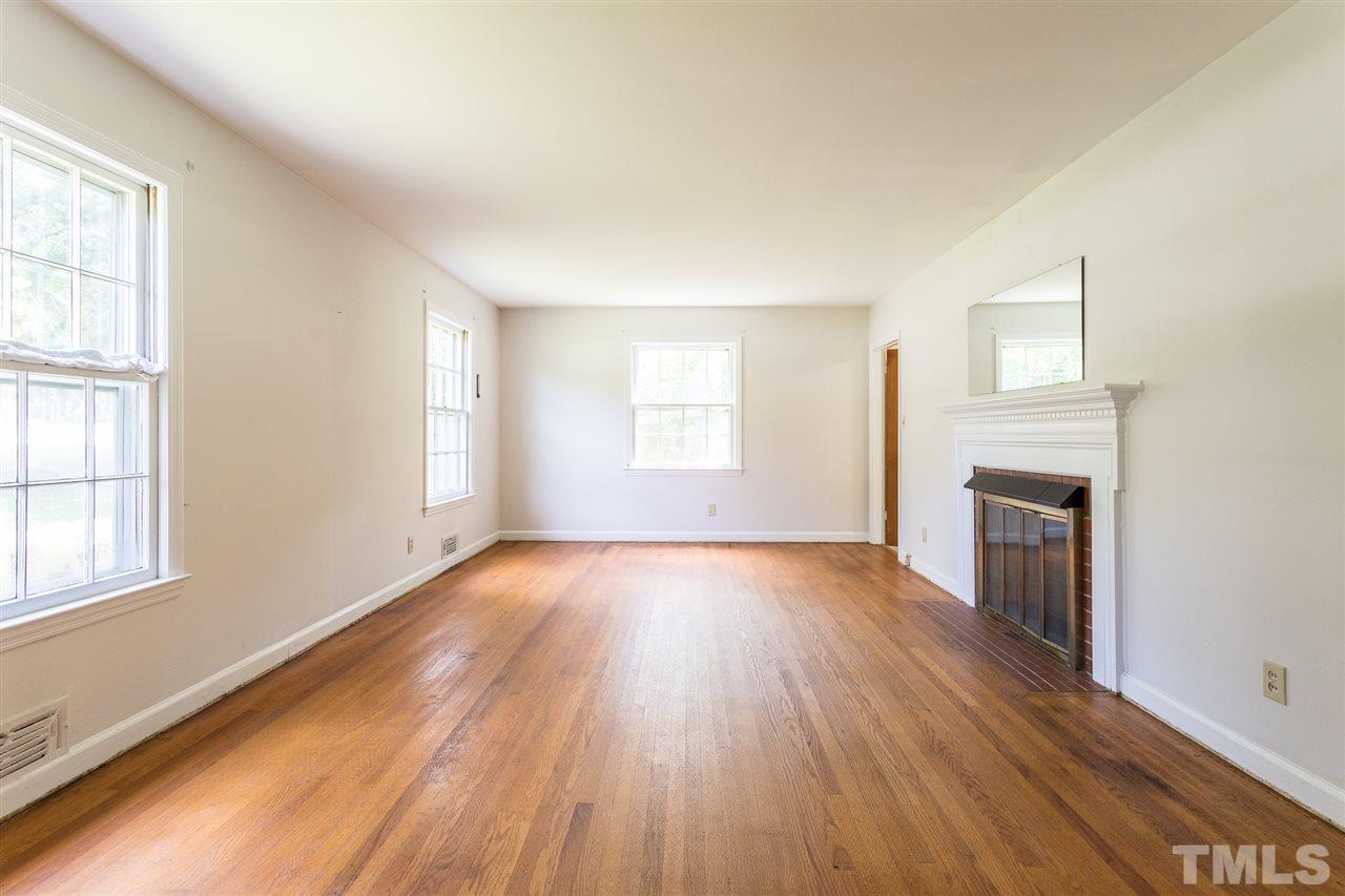 4929 Kaplan Drive Raleigh, NC 27606 - Photo 10 of 30 an empty room with wooden floor fireplace and windows