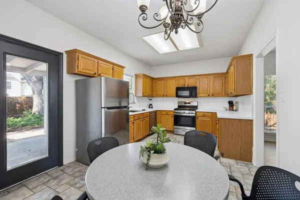 a kitchen with stainless steel appliances granite countertop a refrigerator a stove a sink dishwasher a dining table and chairs with wooden floor