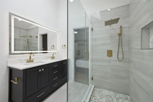 a bathroom with a double vanity sink mirror and shower