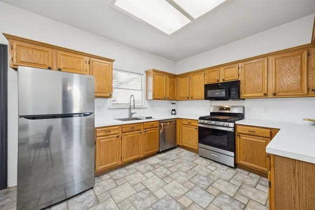 a kitchen with stainless steel appliances granite countertop a refrigerator stove top oven and sink