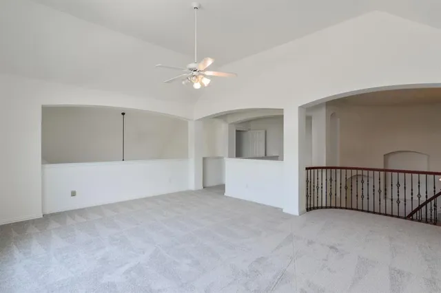 a view of an empty room with chandelier fan