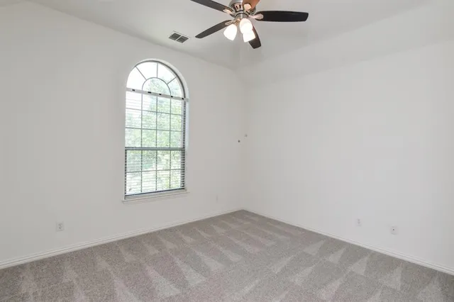 an empty room with a window and a fan