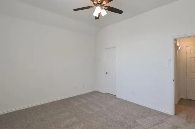 an empty room with a chandelier fan and a ceiling fan