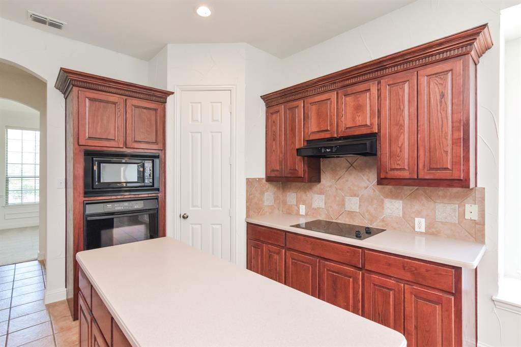 11007 Southwyck Drive Frisco, TX 75033 - Photo 4 of 36 a kitchen with granite countertop wooden cabinets and stainless steel appliances