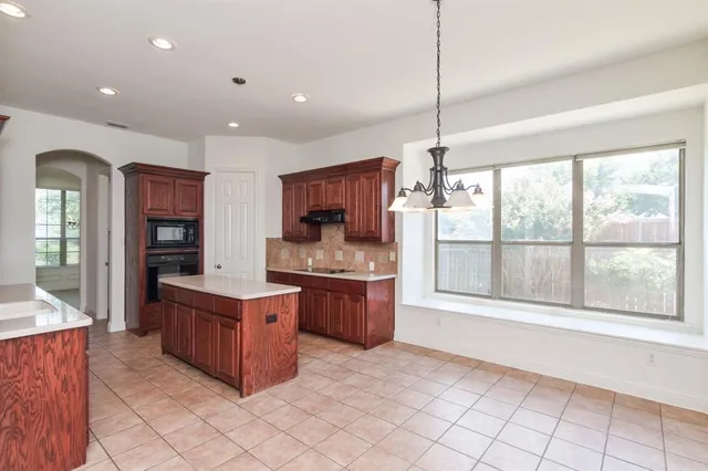 a kitchen with kitchen island granite countertop a stove top oven a sink dishwasher a dining table and chairs with wooden floor