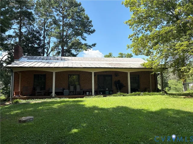 a view of a house with a yard and large trees