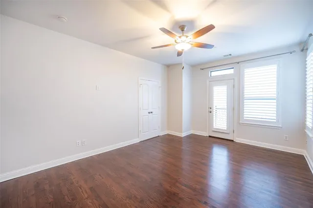 an empty room with wooden floor fan and windows