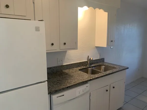 a kitchen with granite countertop white cabinets and a sink