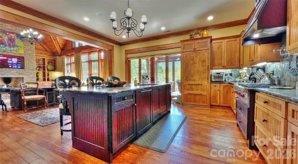 a open kitchen with stainless steel appliances granite countertop a stove dining table and chairs with wooden floor
