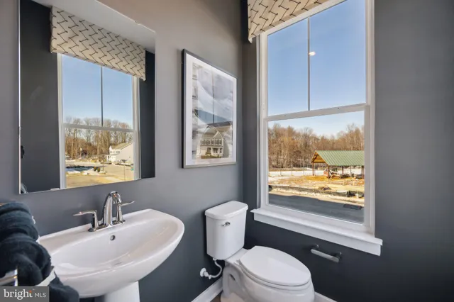 a bathroom with a toilet a sink a mirror and a window