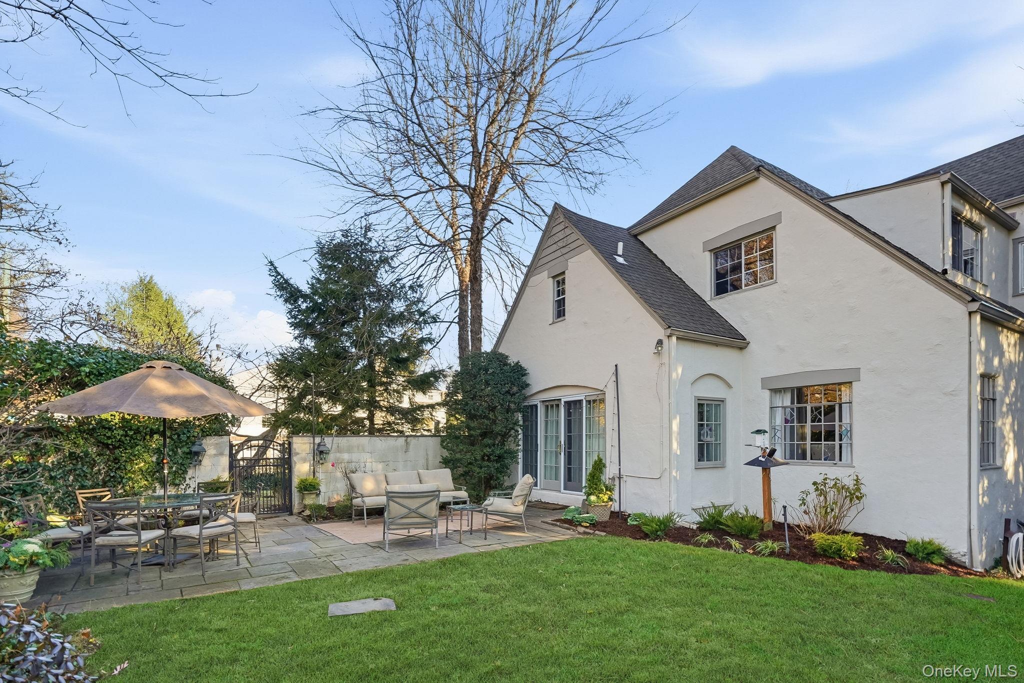1 Oneida Street Rye, NY 10580 - Photo 26 of 32 a view of a white house with a yard and table and chairs under an umbrella