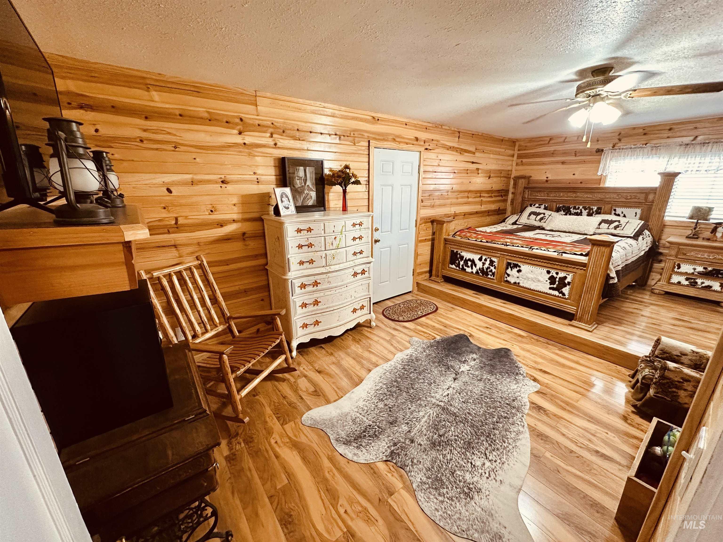 5051 South Rd J Vale, OR 97918 - Photo 11 of 49 Bedroom featuring a textured ceiling, light wood finished floors, a ceiling fan, and wooden walls