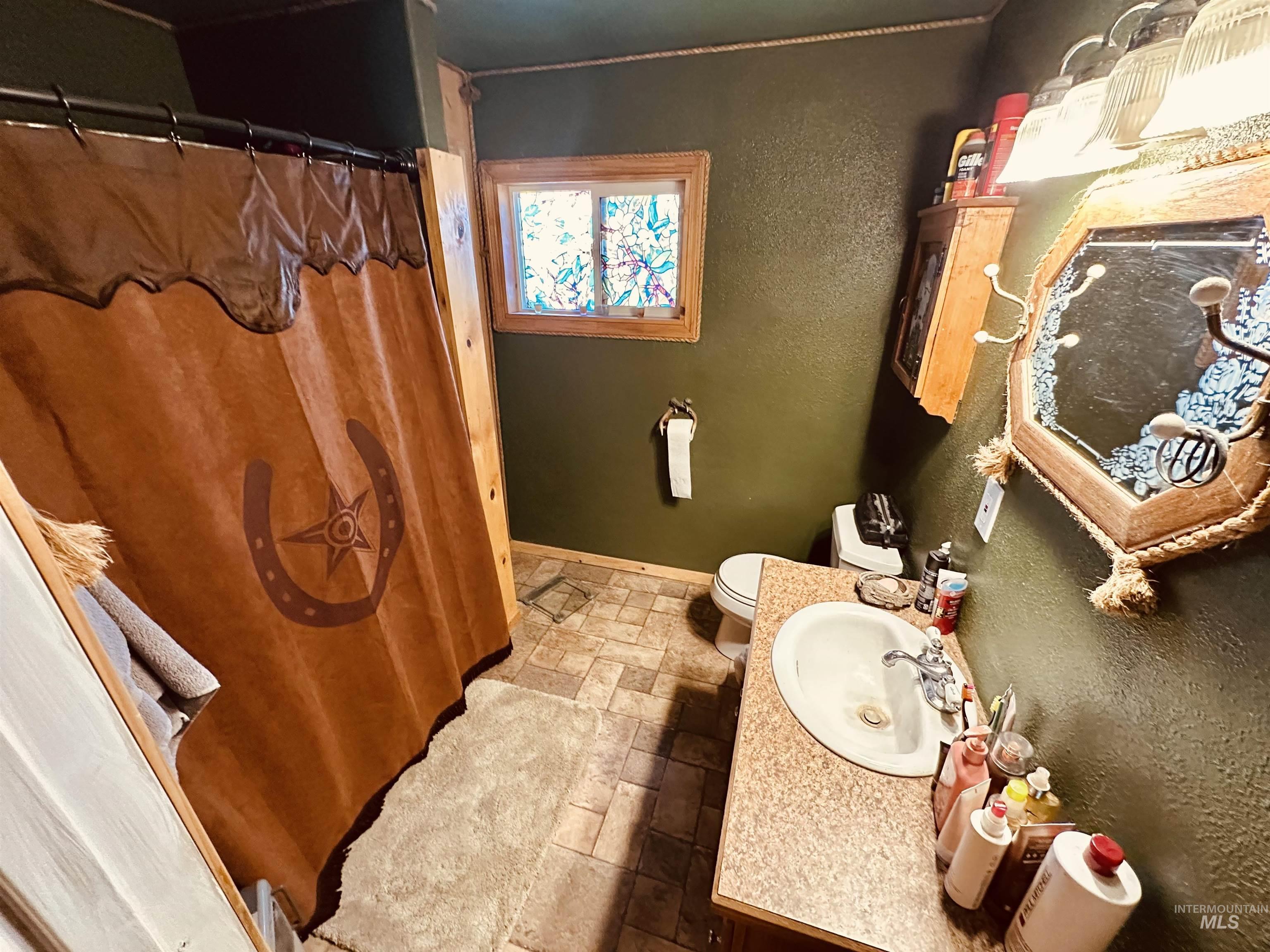 5051 South Rd J Vale, OR 97918 - Photo 13 of 49 Full bath with stone tile floors, vanity, curtained shower, and a textured wall