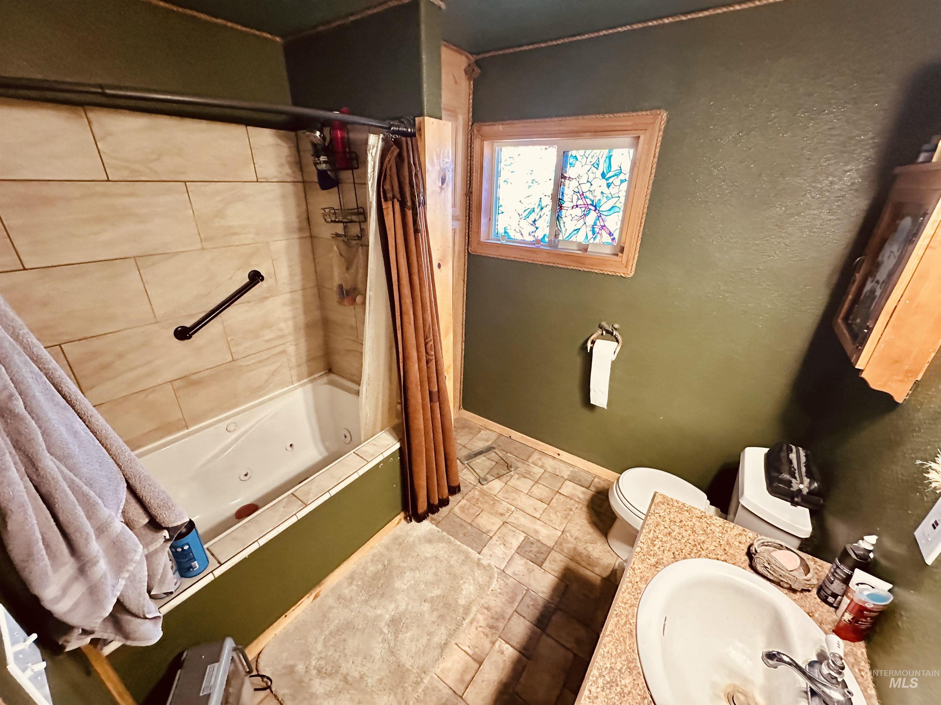 5051 South Rd J Vale, OR 97918 - Photo 14 of 49 Full bathroom featuring a combined bath / shower with jetted tub, vanity, stone tile flooring, and a textured wall