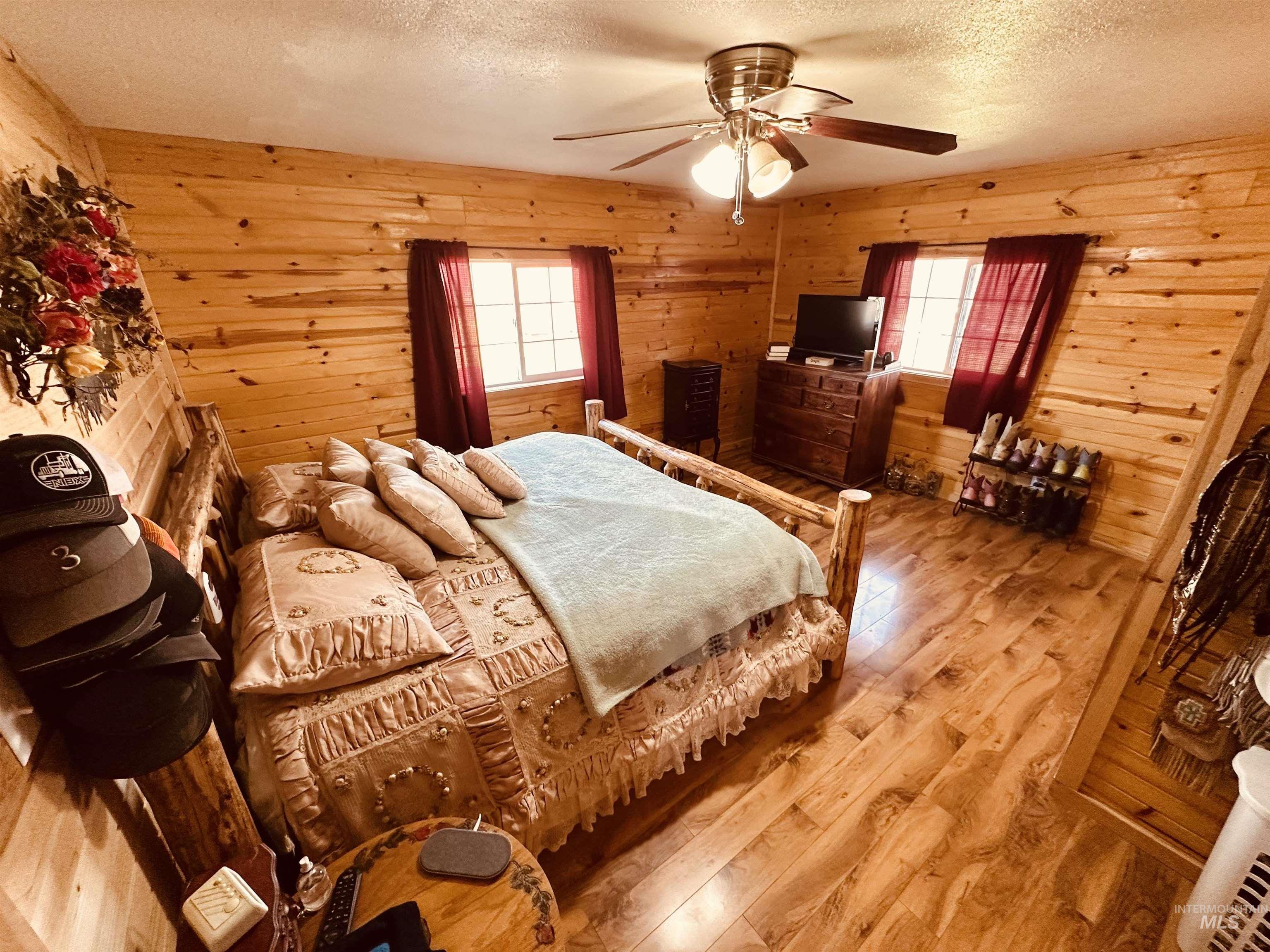 5051 South Rd J Vale, OR 97918 - Photo 15 of 49 Bedroom featuring hardwood / wood-style flooring, a textured ceiling, ceiling fan, multiple windows, and wooden walls