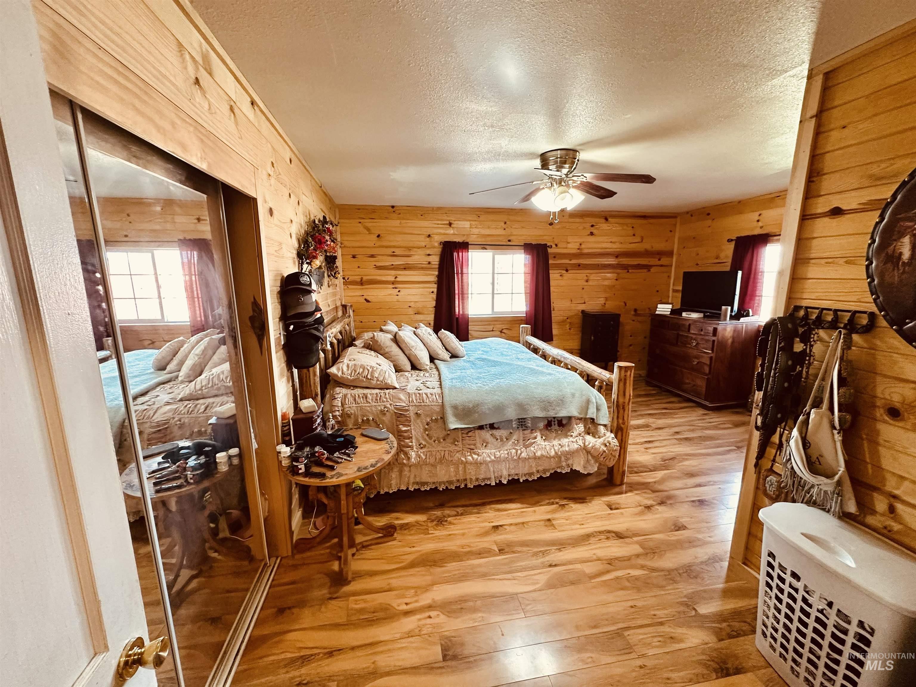 5051 South Rd J Vale, OR 97918 - Photo 18 of 49 Bedroom with a textured ceiling, light wood-style flooring, wood walls, a ceiling fan, and a closet