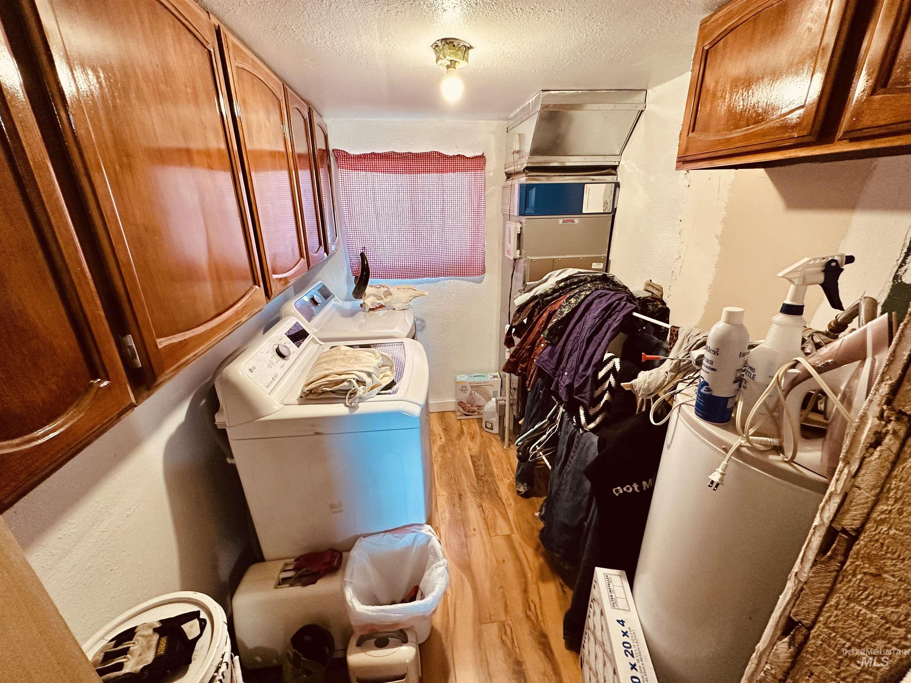 5051 South Rd J Vale, OR 97918 - Photo 22 of 49 Laundry room featuring a textured ceiling, light wood finished floors, washing machine and dryer, and cabinet space