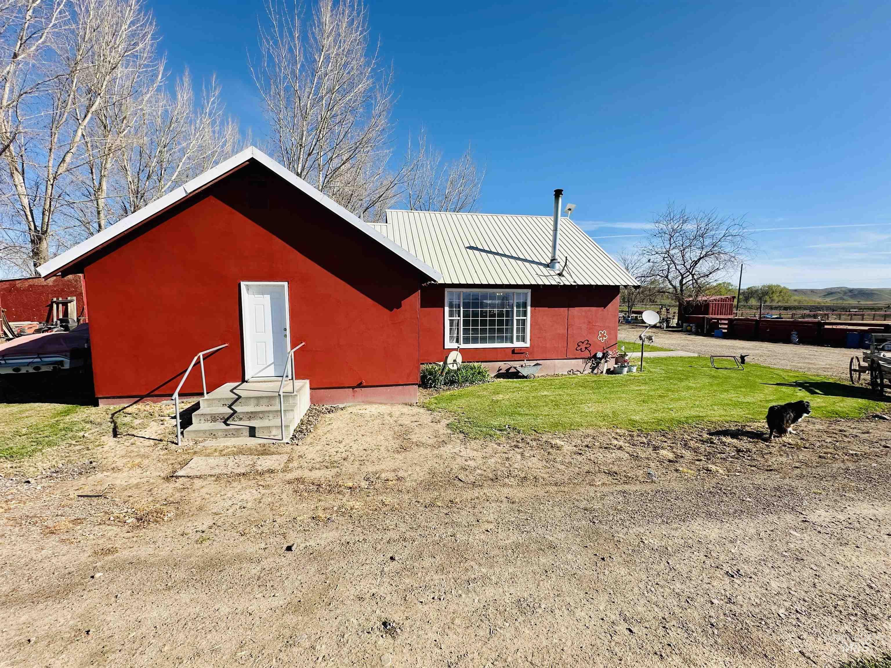 5051 South Rd J Vale, OR 97918 - Photo 31 of 49 Back of house featuring a metal roof, entry steps, stucco siding, and a lawn