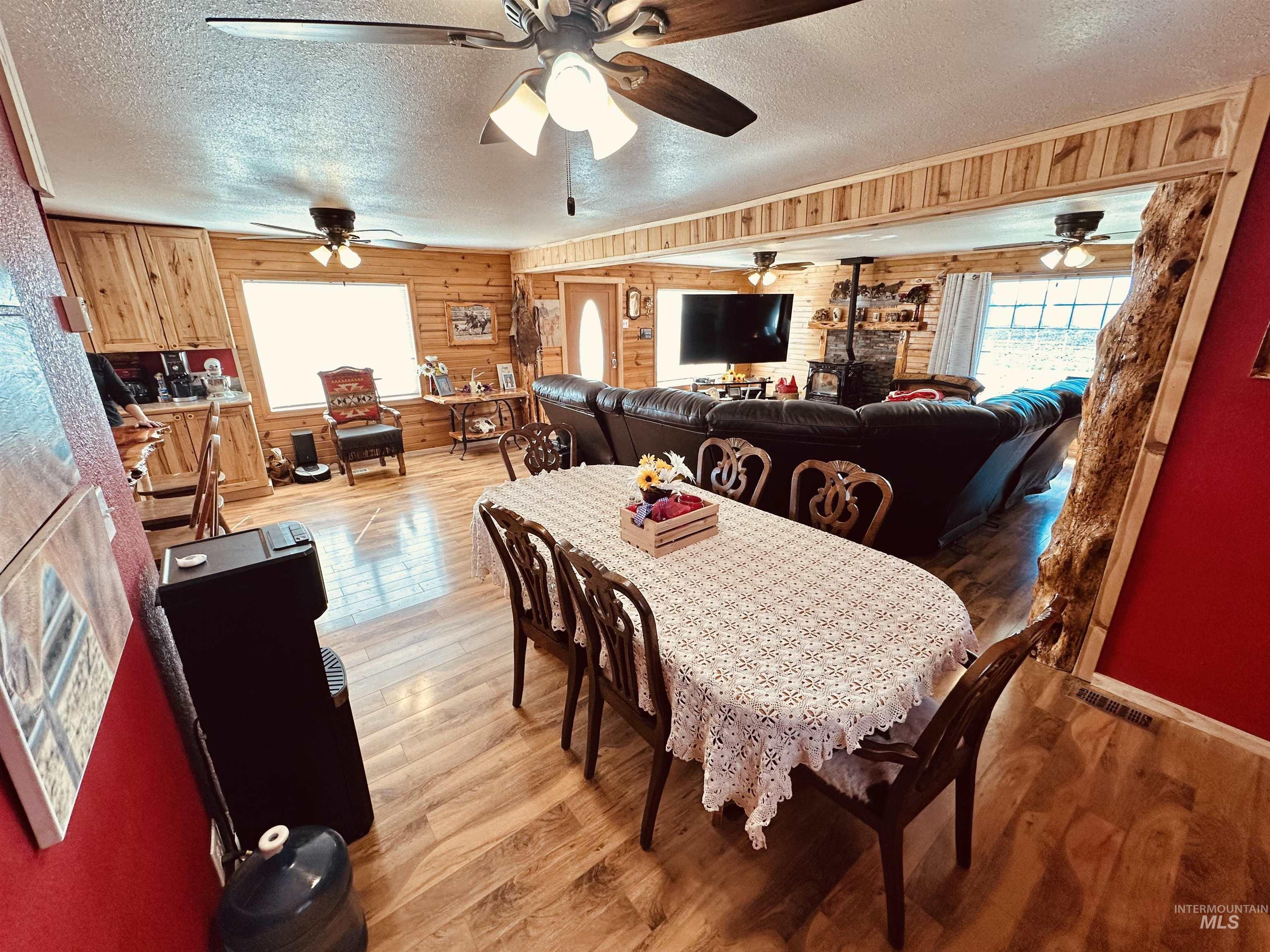 5051 South Rd J Vale, OR 97918 - Photo 6 of 49 Dining room featuring wood walls, a textured ceiling, light wood finished floors, and a ceiling fan