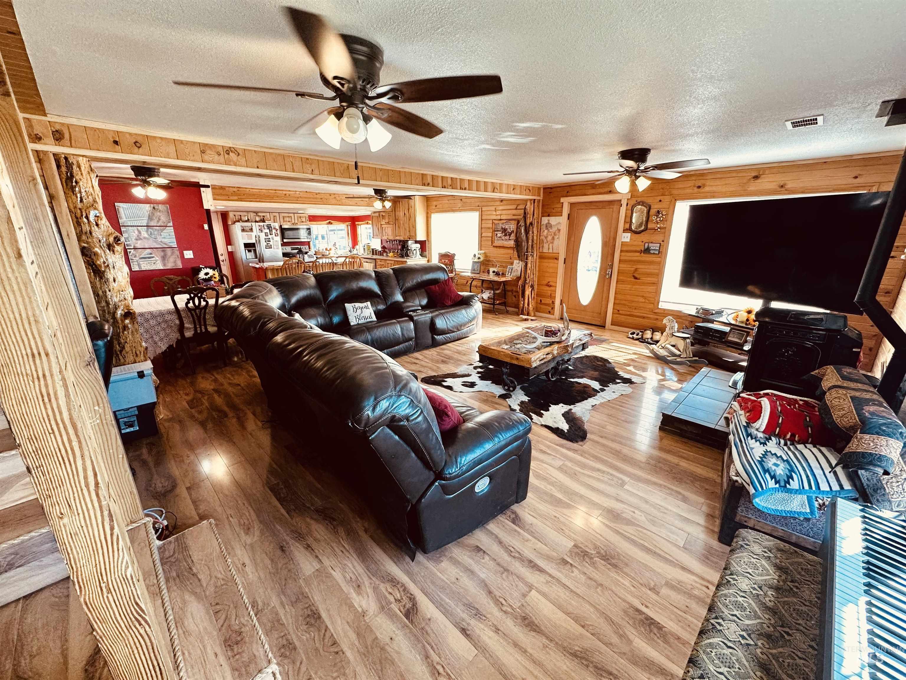 5051 South Rd J Vale, OR 97918 - Photo 7 of 49 Living room featuring wood walls, a textured ceiling, wood finished floors, plenty of natural light, and ceiling fan