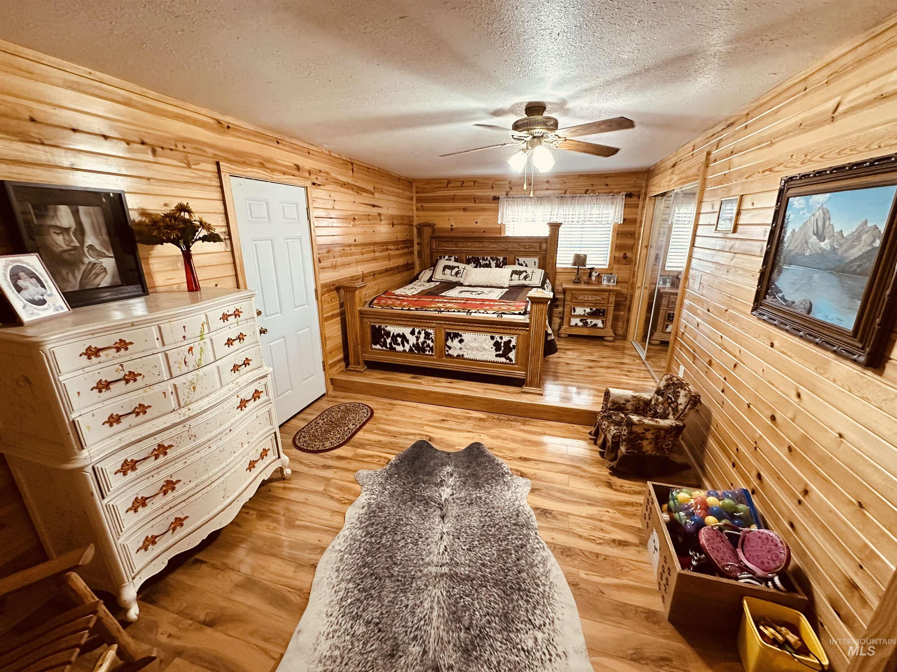 5051 South Rd J Vale, OR 97918 - Photo 10 of 49 Bedroom with wooden walls, a textured ceiling, light wood-type flooring, and a ceiling fan