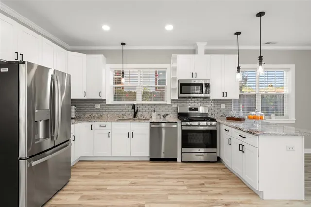 a kitchen with stainless steel appliances granite countertop a refrigerator a stove a sink and a microwave