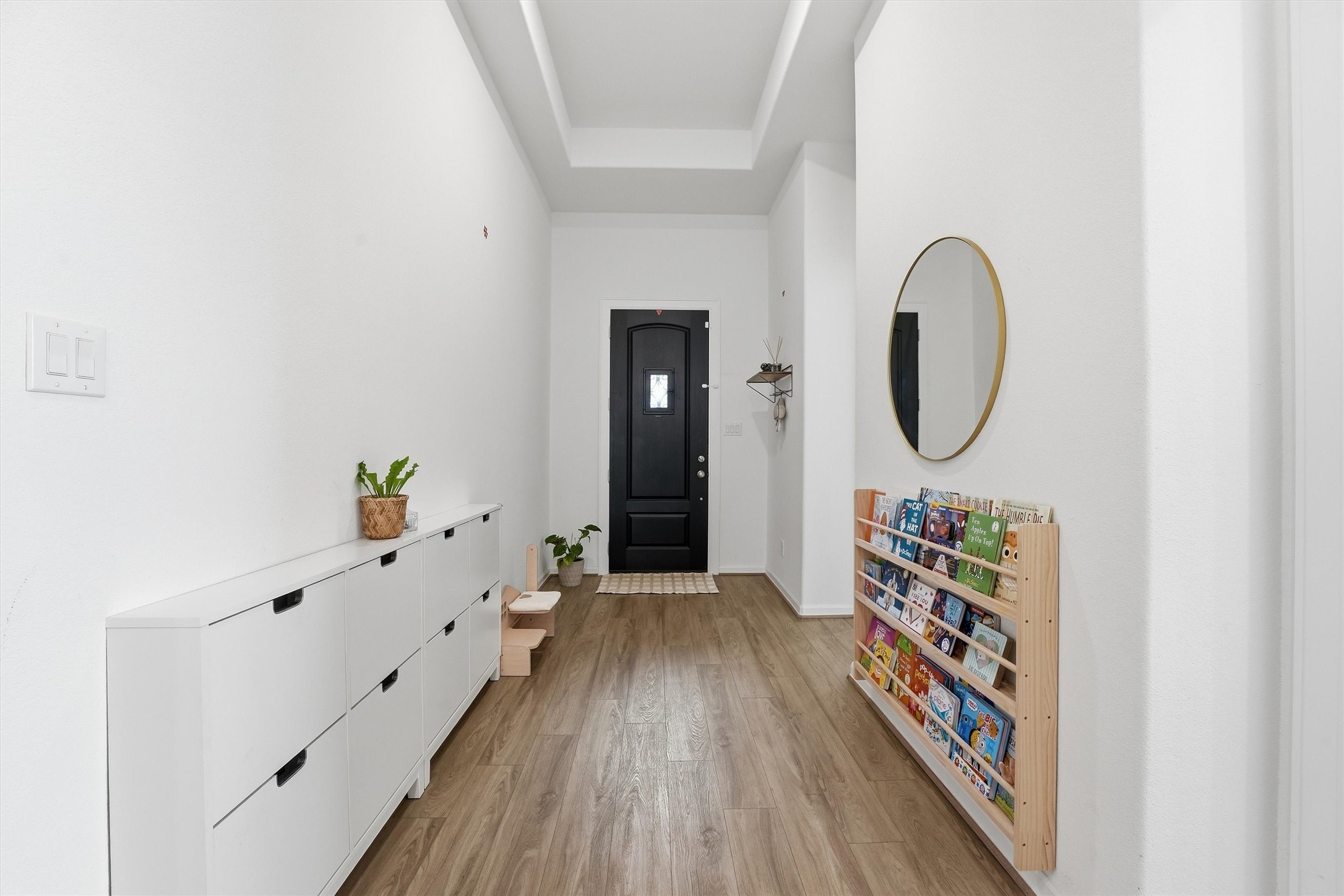 6071 Windward Falls Way Porter, TX 77365 - Photo 4 of 33 Bright and inviting hallway with wood flooring, white walls, and a black front door.