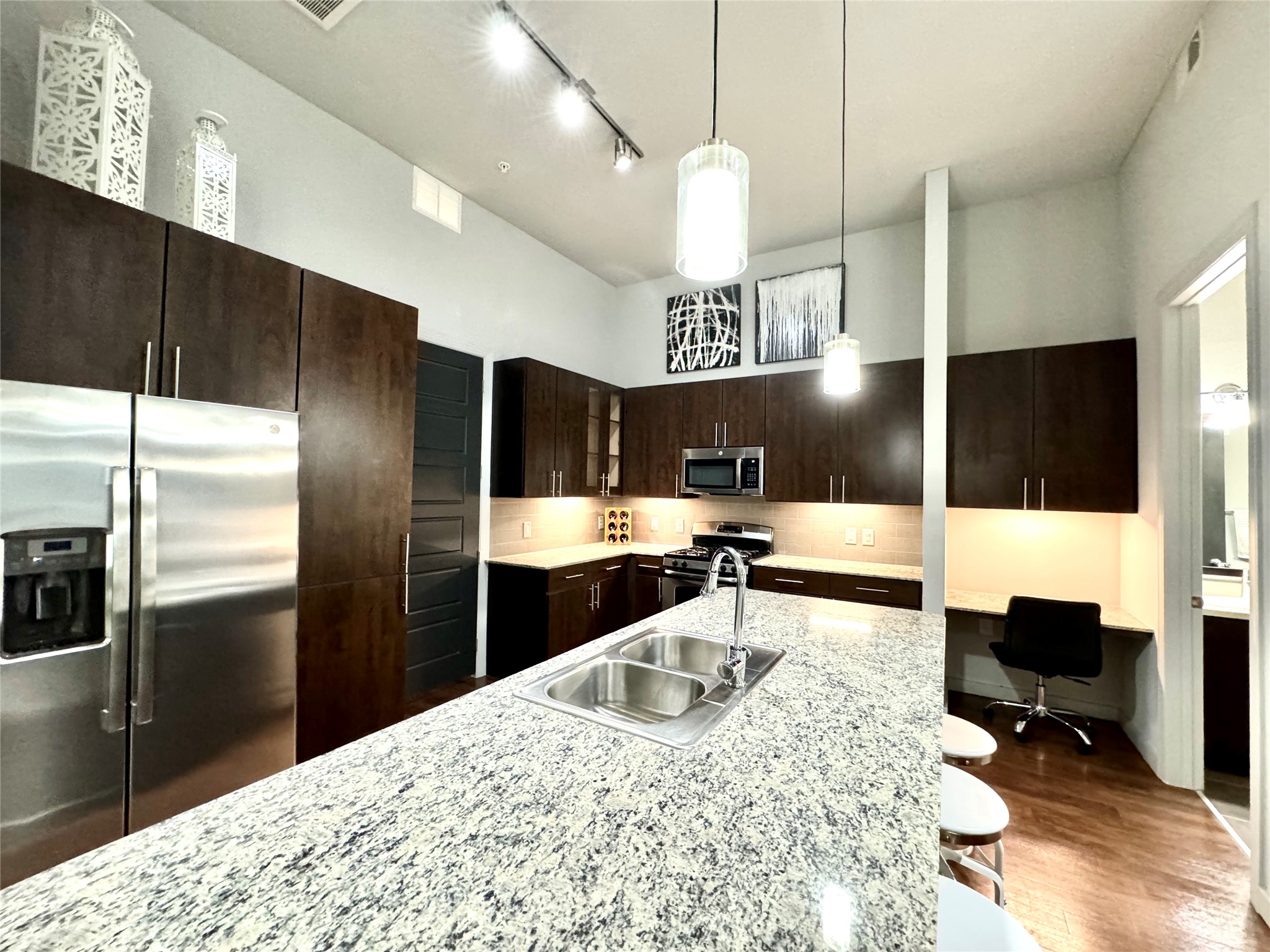 2525 McCue Road, Unit 249 Houston, TX 77056 - Photo 3 of 13 a kitchen with stainless steel appliances kitchen island granite countertop a refrigerator a stove a sink and a dining table with wooden floor