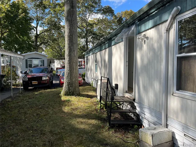 a view of a back yard of the house with a car parked in front of it