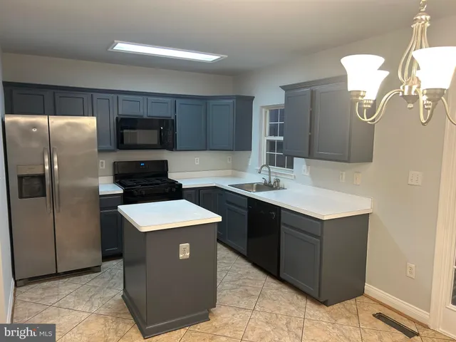 a kitchen with a sink a counter top space stainless steel appliances and cabinets