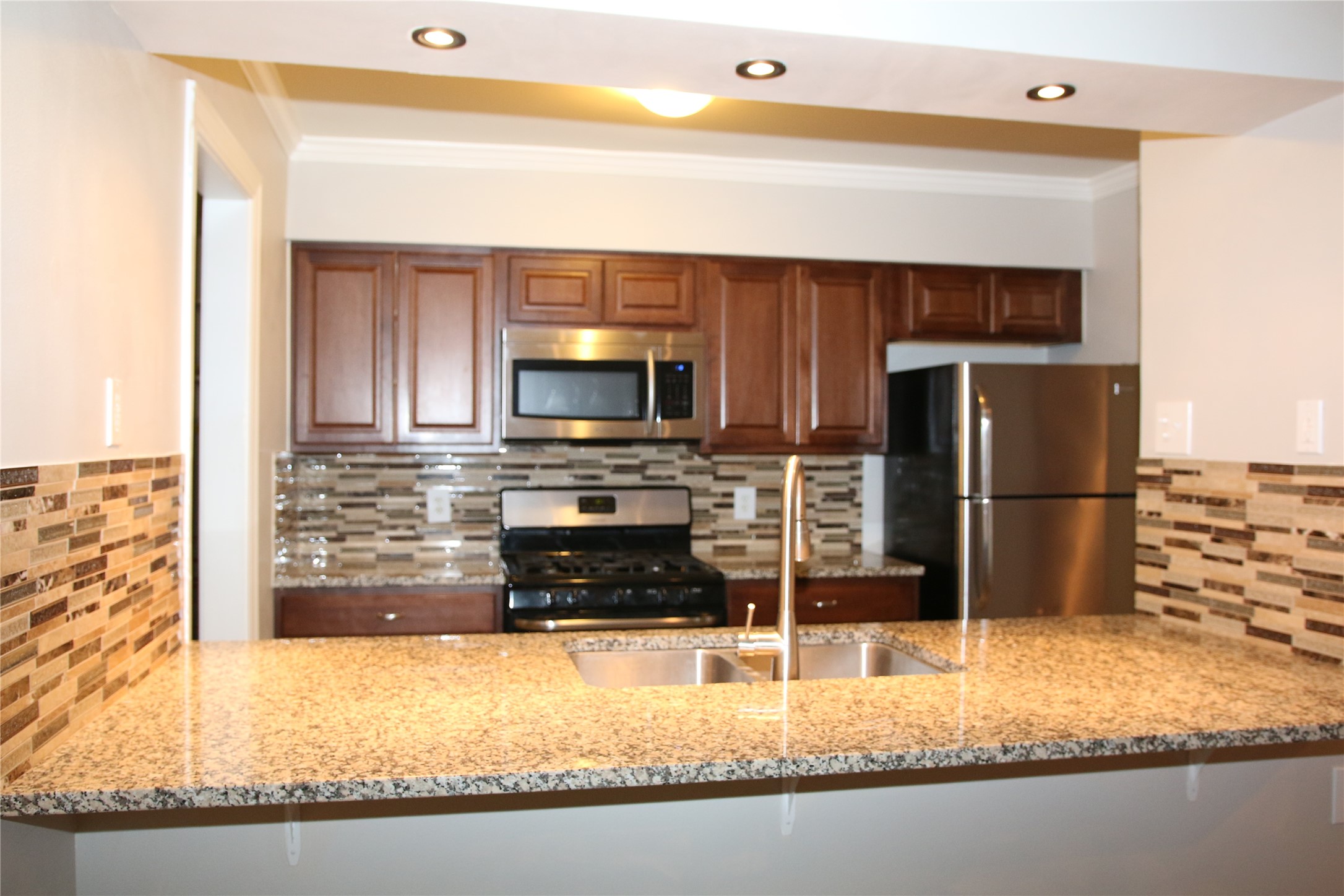 700 Castle Ridge Road, Unit A Austin, TX 78746 - Photo 10 of 34 a kitchen with granite countertop a refrigerator and a stove top oven