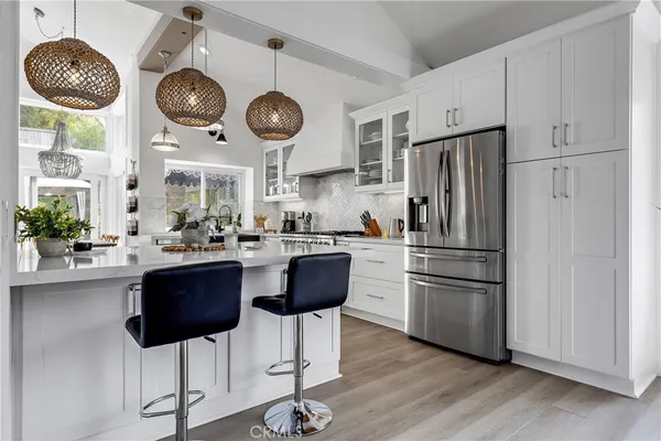 a kitchen with stainless steel appliances a stove a sink a microwave a dining table and chairs with wooden floor