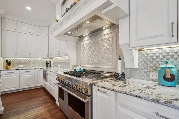 a kitchen with granite countertop a sink stainless steel appliances and white cabinets