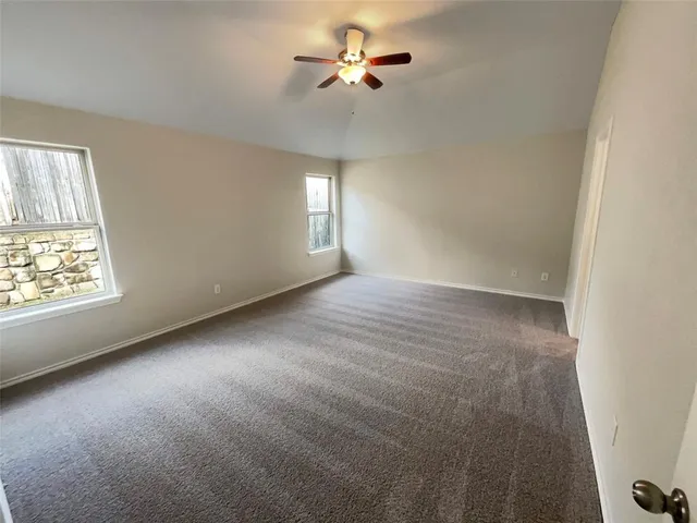 an empty room with windows and fan