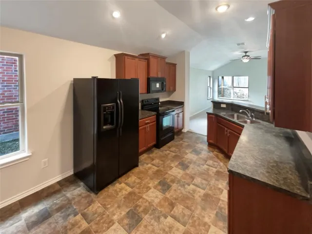 a kitchen with granite countertop a refrigerator and a sink