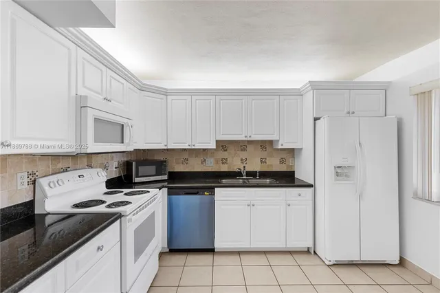 a kitchen with granite countertop white cabinets and white appliances