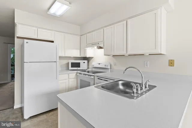 a kitchen with a sink a refrigerator and cabinets