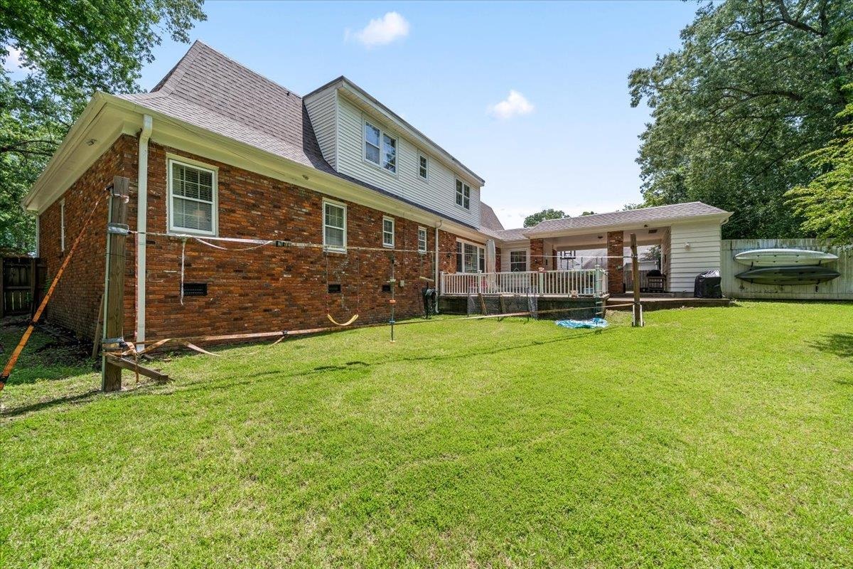 1273 Brookfield Road Memphis, TN 38119 - Photo 37 of 40 Spacious backyard featuring a manicured lawn, brick facade, white siding, a covered patio, and an elevated deck with white railing