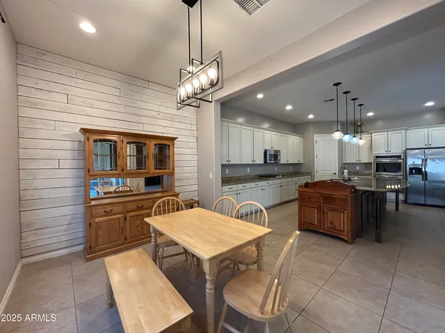 a kitchen with stainless steel appliances granite countertop a sink a stove a kitchen island with chairs and cabinets