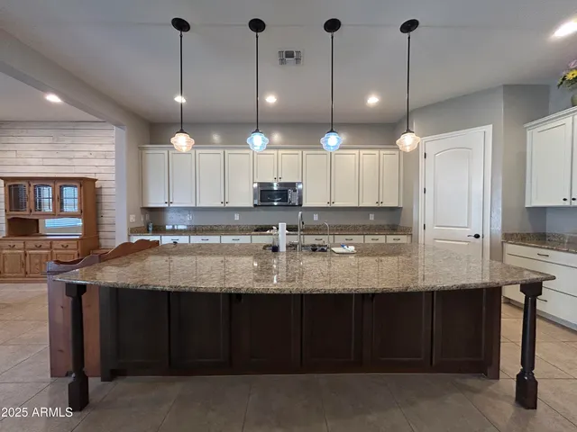 a kitchen with kitchen island granite countertop a sink counter top space cabinets and a chandelier