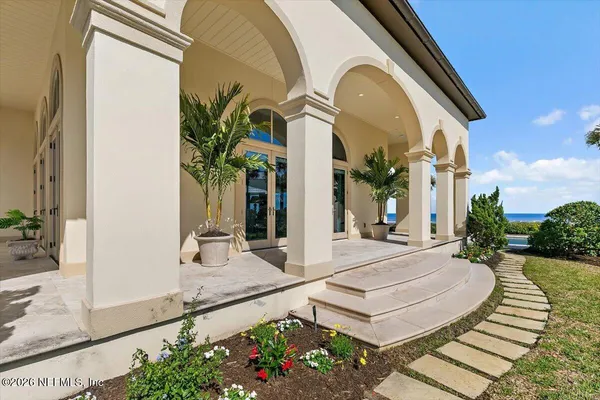 a large white kitchen with granite countertop a large counter top space and stainless steel appliances