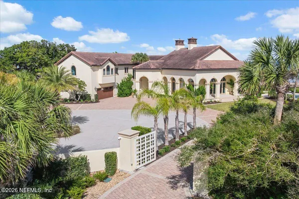 a view of a white house with a yard plants and large tree
