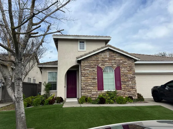 a view of a house with brick walls and a yard with plants