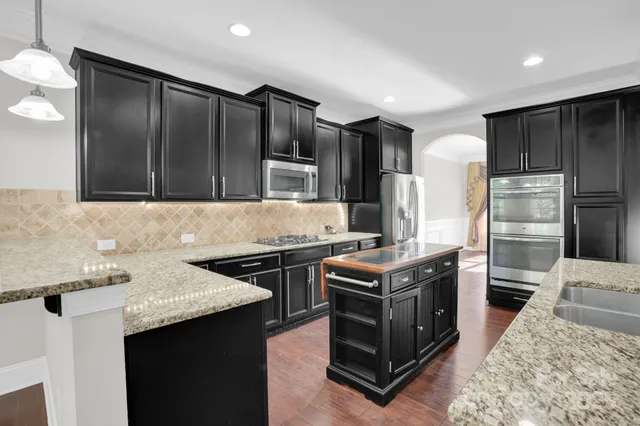 a kitchen with stainless steel appliances granite countertop a stove a sink and a refrigerator