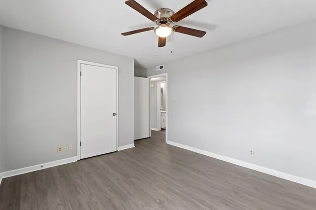 an empty room with wooden floor and a ceiling fan