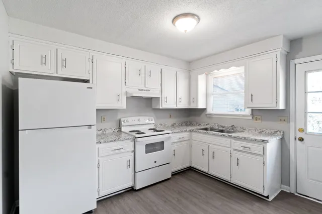 a kitchen with white cabinets white appliances and sink
