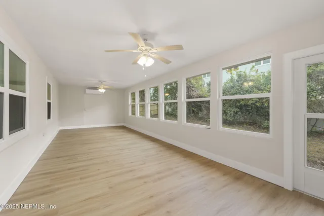 a view of an empty room with a window and wooden floor