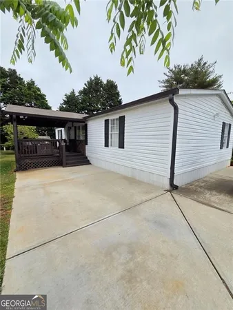 a view of house with backyard and trees in the background