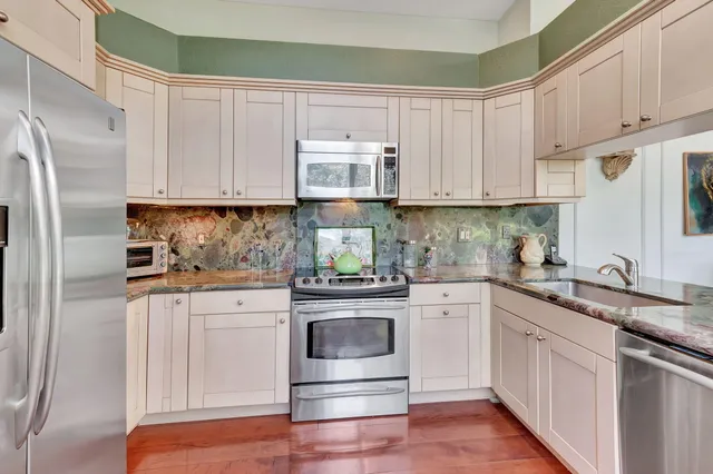 a kitchen with stainless steel appliances granite countertop a refrigerator and a stove top oven