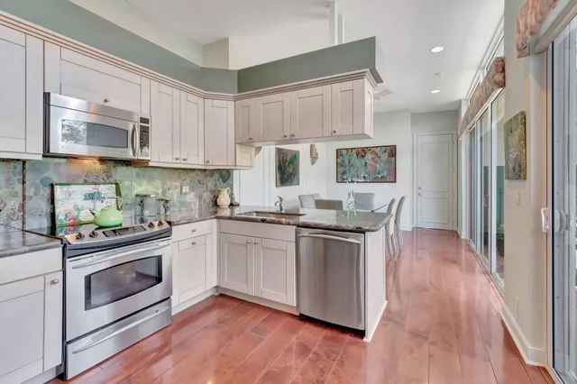 a kitchen with stainless steel appliances granite countertop a table chairs in it and wooden floors